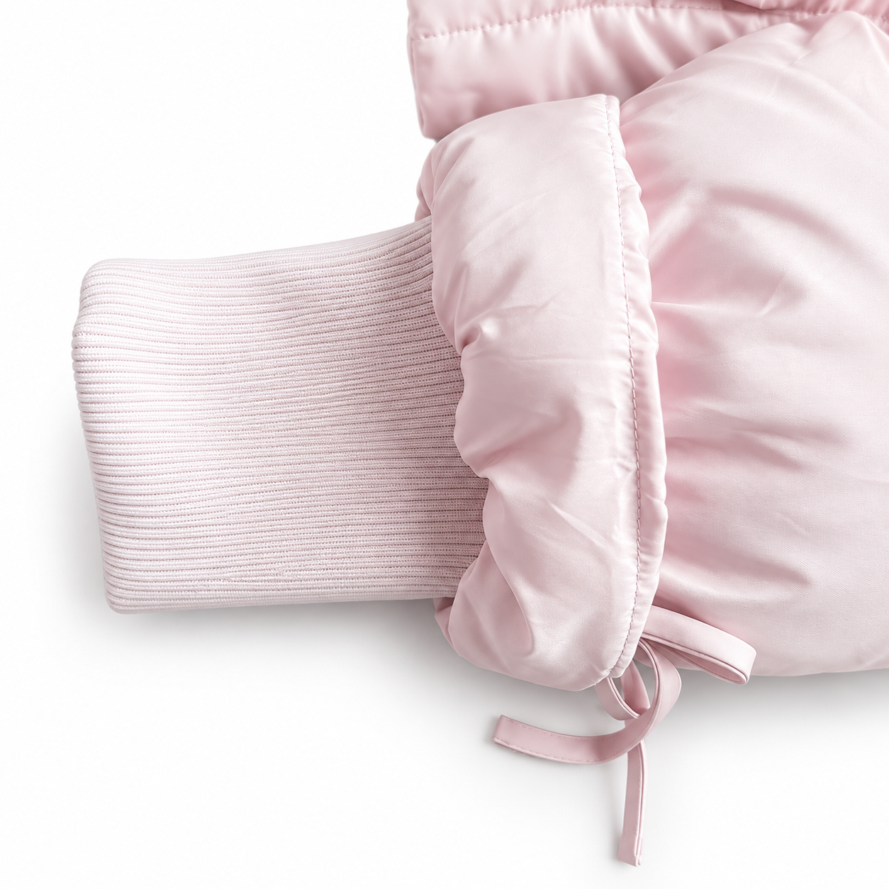 Close-up of a light pink puffer jacket sleeve with a ribbed knit cuff and drawstring detail, shown on a white background.